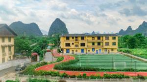 a building with a tennis court in front of mountains at Guilin Meishe Homestay in Guilin