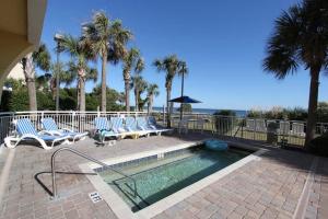 - une piscine avec des chaises longues et des palmiers dans l'établissement Camelot By The Sea Ocean Front Condo, à Myrtle Beach