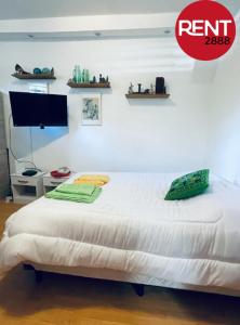 1 dormitorio con 1 cama blanca y TV en Rent Ugarte en Buenos Aires