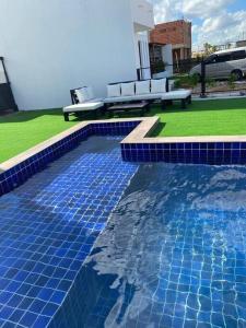 a swimming pool with blue tiles and a bench at Bella casa de playa Mar Adentro in Santa Cruz de la Sierra