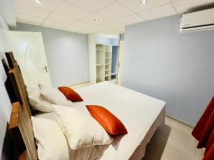 - une chambre avec un lit blanc et des oreillers orange dans l'établissement Maison T3 Nid Bleu - Piscine Privée, au Marin
