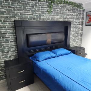 uma cama com uma cabeceira preta e uma parede de tijolos em El Hostalito Metepec em Toluca