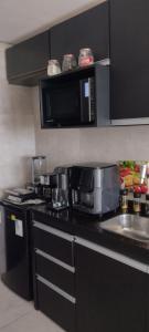 a kitchen with a black counter top with a microwave at Luxury Paiva Flat in Recife