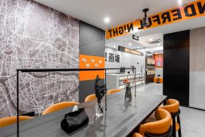 a dining room with a table and orange chairs at Banana Fun Hotel - Guangzhou East Railway Station Yantang Metro Station in Guangzhou