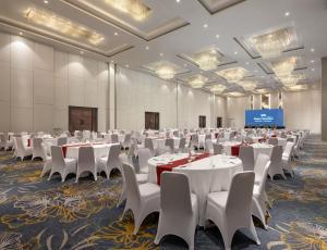 a large banquet hall with tables and white chairs at Hotel Santika Premiere Gubeng Surabaya in Surabaya