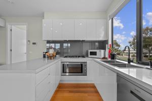 a white kitchen with a stove top oven next to a window at Churchill Delux, close to Western health 10 min to Cbd in Braybrook