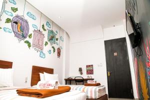 マナドにあるIstanaku Guesthouse 2のベッドルーム1室(ベッド2台、壁掛けテレビ付)
