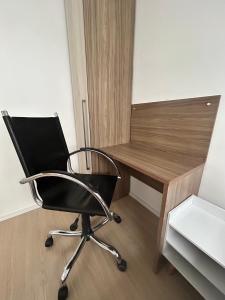 una sedia nera seduta accanto a una scrivania di legno di Apto Allianz Metrô Barra Funda a San Paolo