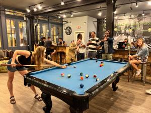 a group of people standing around a pool table at Apple Hostels of Philadelphia in Philadelphia
