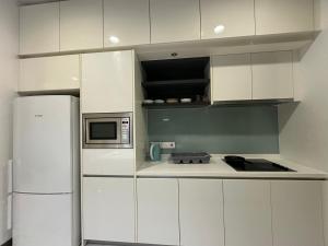 a white kitchen with a refrigerator and a microwave at Platinum suites by BLUE SKY in Kuala Lumpur