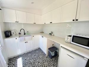 cocina con armarios blancos y microondas en Mapleton Park Cottage en Springwood