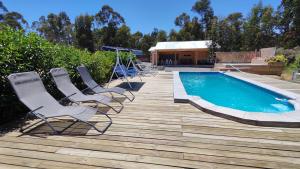 a deck with chairs and a swimming pool at Casa Charlotte in San José