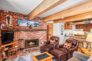 a living room with a brick fireplace and leather chairs at Chateau DuMont 05 in Aspen +27 photos