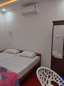 1 dormitorio con 1 cama, ventilador y silla en Isha Marari Beach homestay, en Mararikulam