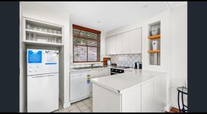 a kitchen with white cabinets and a white refrigerator at Villa 2br Shiraz Villa located within Cypress Lakes Resort in Pokolbin