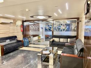 a living room with couches and a glass table at HOTEL REST INN in Surat