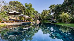 a swimming pool with chairs and umbrellas in a yard at Sala Lodges in Siem Reap