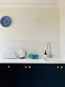 a kitchen counter with blue cabinets and a sink at Summit House Armidale - 2 or 4 Bedrooms in Armidale