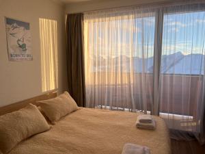 a bedroom with a bed and a large window at Twins #144 New Gudauri with Mountain View in Gudauri