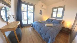 um quarto com uma cama azul, uma secretária e janelas em a front beach cottage in a protected area em Mesolongion