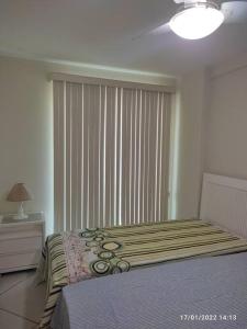 ein Schlafzimmer mit einem Bett und einem großen Fenster in der Unterkunft Apartamento encantador a 250 m da Praia do Forte in Cabo Frio