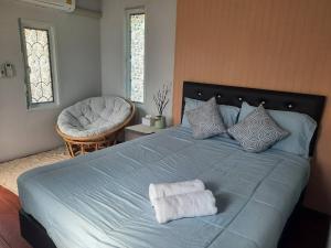 a bedroom with a blue bed with two towels on it at Homlomchomsuan หอมลมชมสวน in Ban Mai