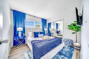 a bedroom with blue curtains and a large bed at Chic and Central Condo - Palm Wave Says in Coconut Creek