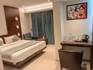 a hotel room with a bed and a desk at Pride Biznotel Alkapuri Near Vadodara Airport in Vadodara +81 photos