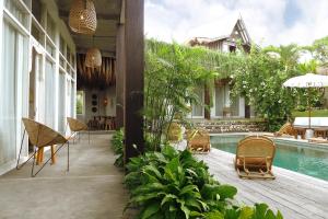 a patio with chairs and a swimming pool at Amar Boutique Hotel in Canggu