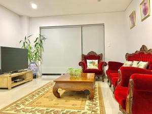 un soggiorno con sedie rosse e TV a schermo piatto di Bankstown 4 Br house close to Shopping & Station a Bankstown
