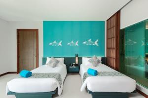 a bedroom with two beds and a blue wall at Fishermens Harbour Urban Resort - SHA Extra Plus in Patong Beach