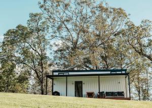 a small white building on a hill with trees at Tiny Zoe in Mount George