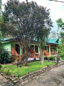 uma casa com uma árvore em frente em Wisma Batu Mandi and offers jungle tours em Bukit Lawang