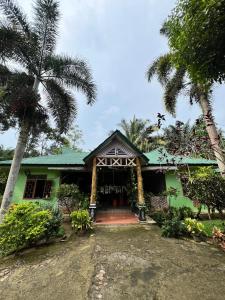 una casa verde con palme di fronte di Wisma Batu Mandi and offers jungle tours a Bukit Lawang