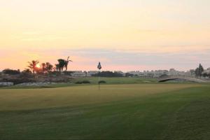 Blick auf einen Golfplatz bei Sonnenuntergang in der Unterkunft Luxurious three-bedroom Villa. in Ras al Khaimah