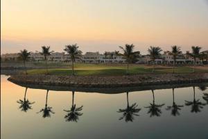 eine Reflexion eines Golfplatzes im Wasser in der Unterkunft Luxurious three-bedroom Villa. in Ras al Khaimah
