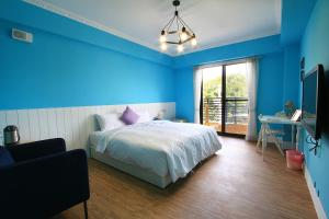 墾丁的住宿－优閒民宿，一间蓝色卧室,配有一张床、一张书桌和一台电视