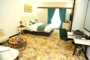 Habitación de hotel con cama, sofá y escritorio en Faletti's Grand Hotel Multan, en Multán