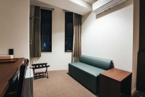 a living room with a green couch and windows at TAPSTAY HOTEL - Vacation STAY 35239v in Saga