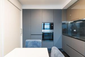 a kitchen with a white table and blue chairs at WelcomeBuddy - SeaLux Apartment in São Roque