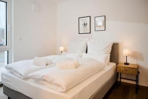 a large white bed with white sheets and pillows at Casa Materi - Barrierearme Apartments in Bad Kissingen