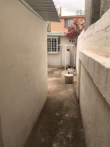 an alley with a white wall and a house at Habitacion #1 in Chihuahua