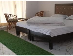 a bedroom with a bed with white sheets and a green rug at Hotel PJ Dupeex, Ravigram, Phata in Phata