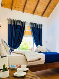 a bedroom with blue curtains and a bed with a table at Star Holiday Home in Nuwara Eliya