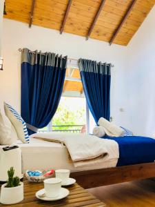 1 dormitorio con cortinas azules y 1 cama con mesa en Star Holiday Home, en Nuwara Eliya