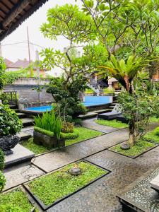 a garden with trees and plants on a sidewalk at Aura Bisma Guesthouse in Ubud