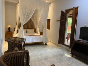 a bedroom with a bed with curtains and a tv at Aura Bisma Guesthouse in Ubud