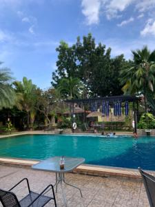 a swimming pool with two chairs and a table at Park & Pool Resort in Nong Khai