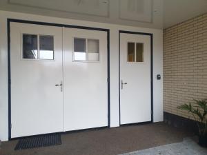 dos puertas blancas de garaje con ventanas en una pared de ladrillo en Suite De Brinkparel en De Koog