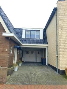 a brick house with a garage with a driveway at Suite De Brinkparel in De Koog
